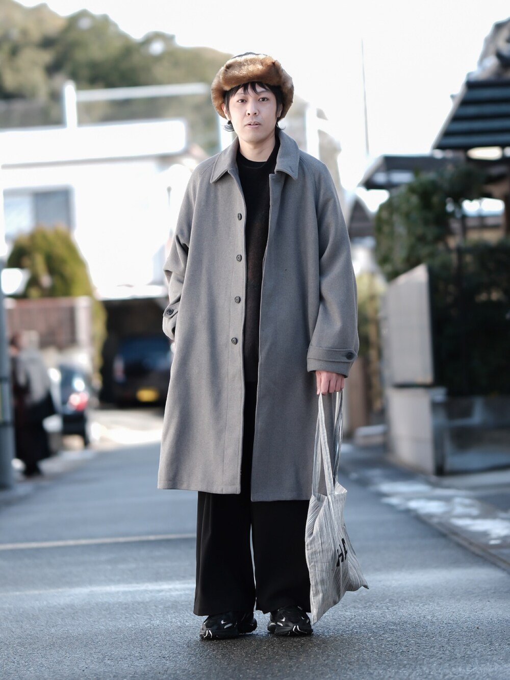 ブラウン系のニット/セーター、ベージュ系のステンカラーコート、ブラック系のその他パンツを着用したメンズの冬コーディネートの2枚目の写真