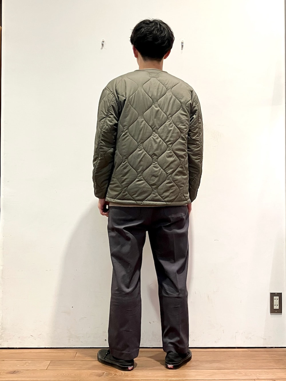 グリーン系のダウンジャケット/コート、ベージュ系のニット/セーター、グレー系のその他パンツを着用したメンズの秋コーディネートの3枚目の写真