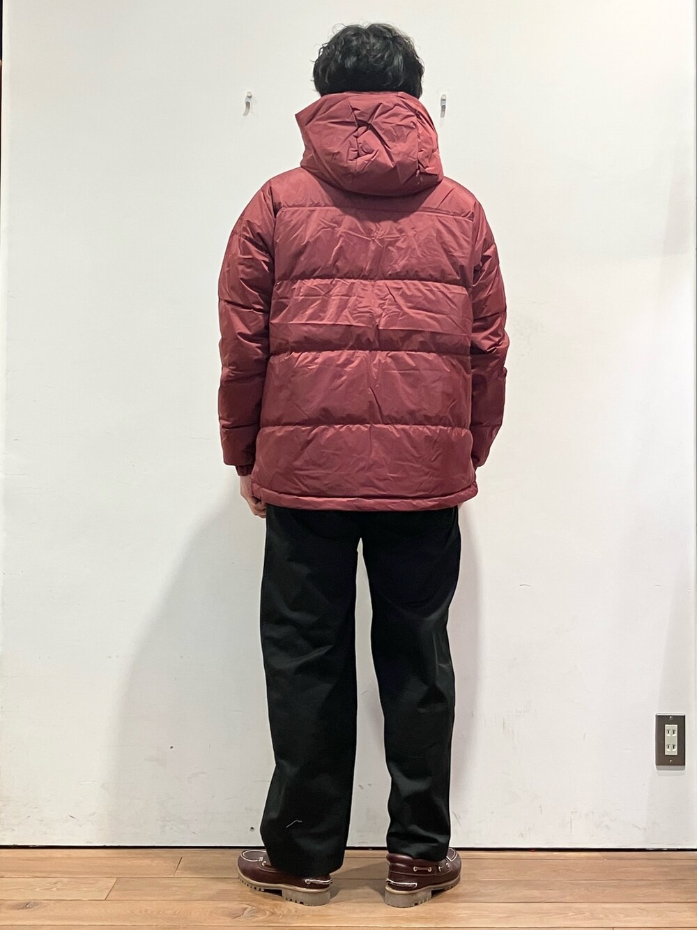 レッド系のダウンジャケット/コート、ベージュ系のTシャツ/カットソー、ブラック系のチノパンツを着用したメンズの秋コーディネートの4枚目の写真