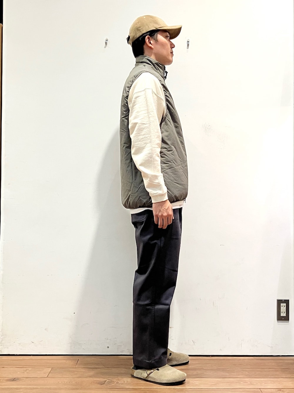 ベージュ系のダウンベスト、ベージュ系のスウェット、グレー系のその他パンツを着用したメンズの秋コーディネートの3枚目の写真