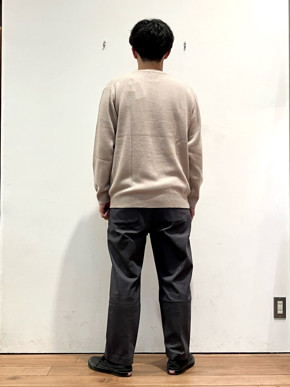 グリーン系のダウンジャケット/コート、ベージュ系のニット/セーター、グレー系のその他パンツを着用したメンズの秋コーディネートの6枚目の写真