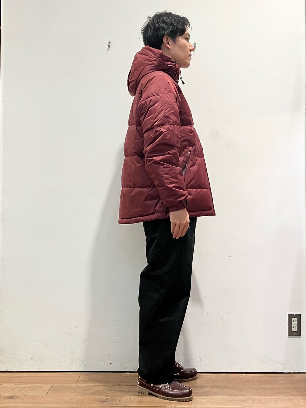 レッド系のダウンジャケット/コート、ベージュ系のTシャツ/カットソー、ブラック系のチノパンツを着用したメンズの秋コーディネートの3枚目の写真