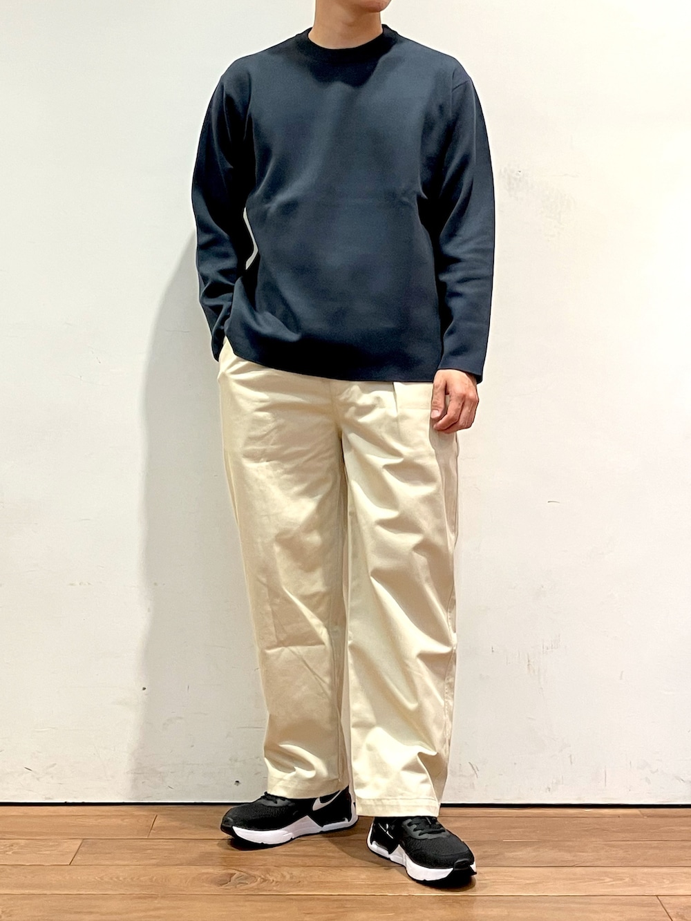 グリーン系のナイロンジャケット、ブルー系のニット/セーター、ホワイト系のチノパンツを着用したメンズの秋コーディネートの4枚目の写真