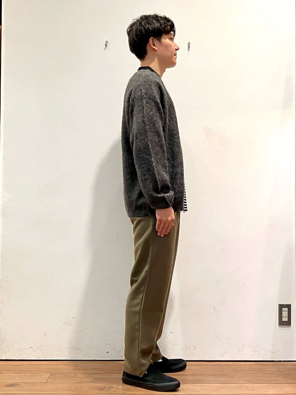 グレー系のカーディガン/ボレロ、ホワイト系のTシャツ/カットソー、グリーン系のパンツを着用したメンズの秋コーディネートの2枚目の写真