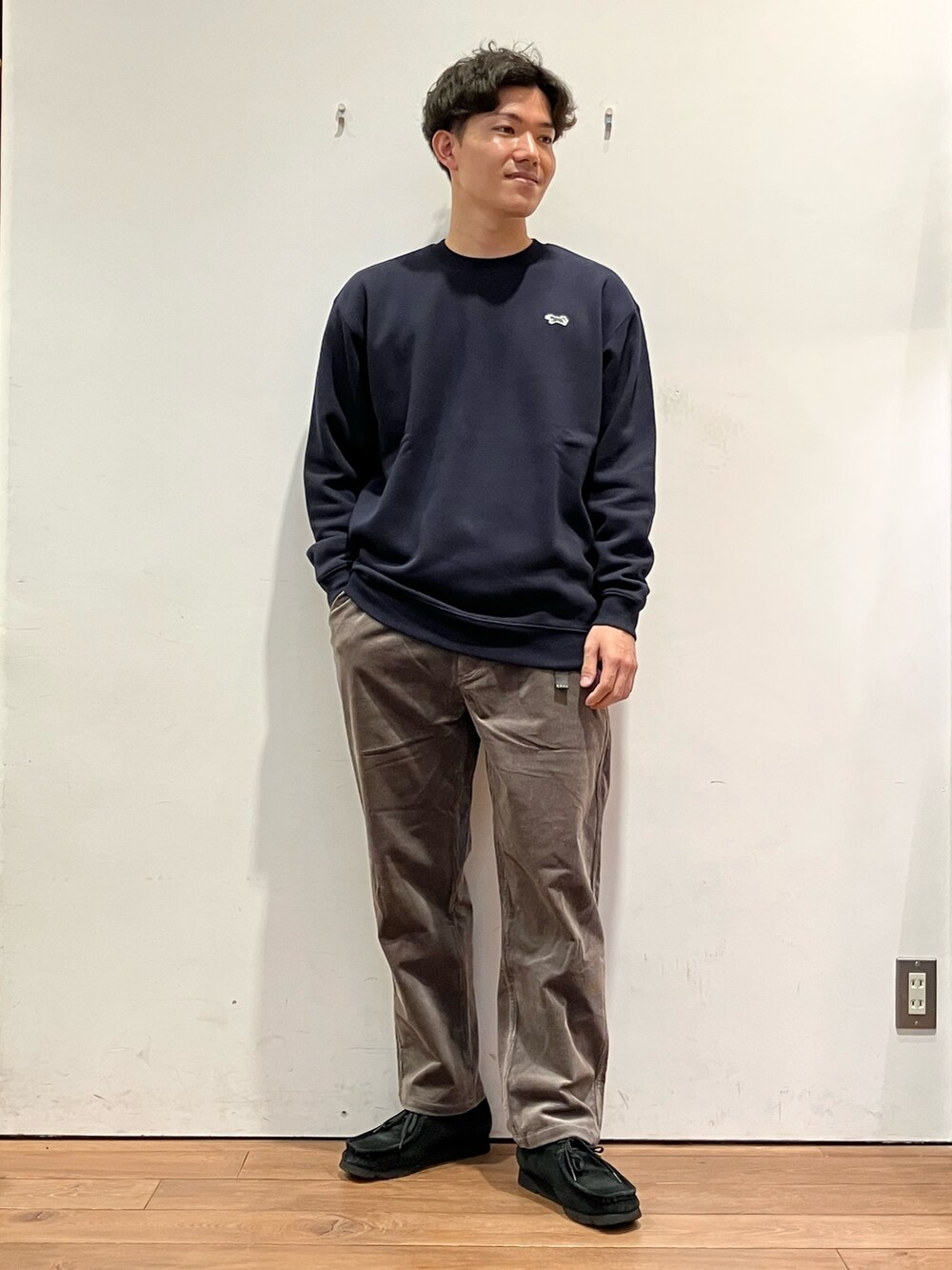 ベージュ系のベスト、ブルー系のスウェット、ブラウン系のパンツを着用したメンズの秋コーディネートの4枚目の写真