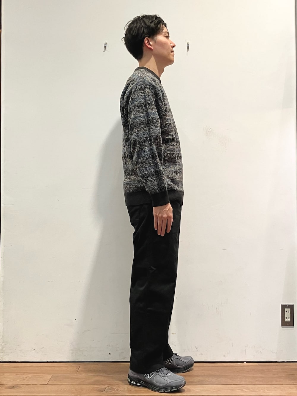 ブルー系のダウンジャケット/コート、ブラック系のチノパンツ、グレー系のニット/セーターを着用したメンズの秋コーディネートの5枚目の写真