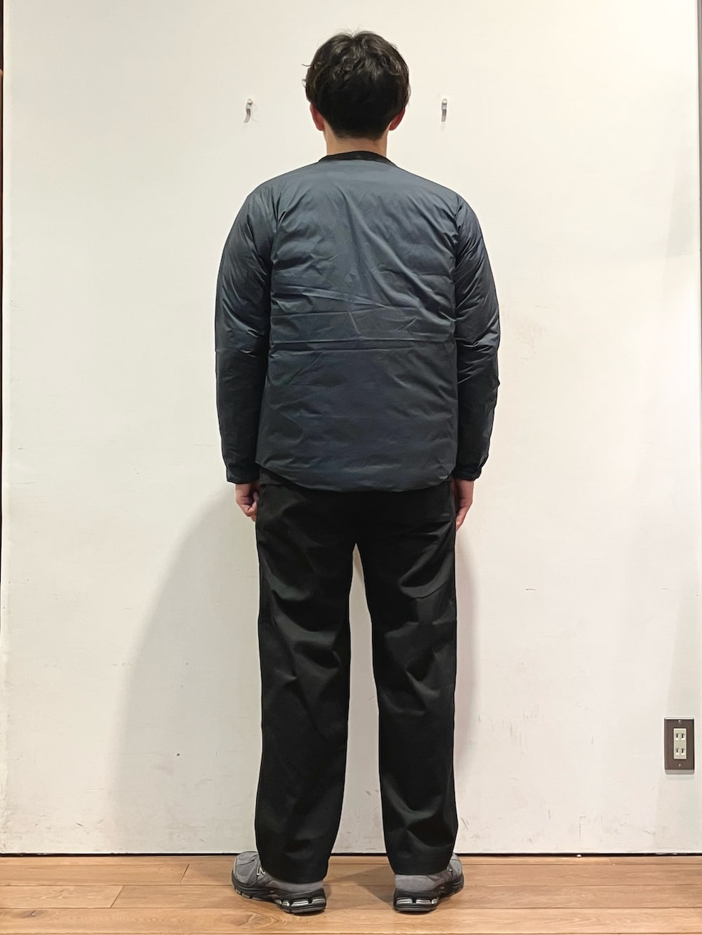 ブルー系のダウンジャケット/コート、ブラック系のチノパンツ、グレー系のニット/セーターを着用したメンズの秋コーディネートの3枚目の写真