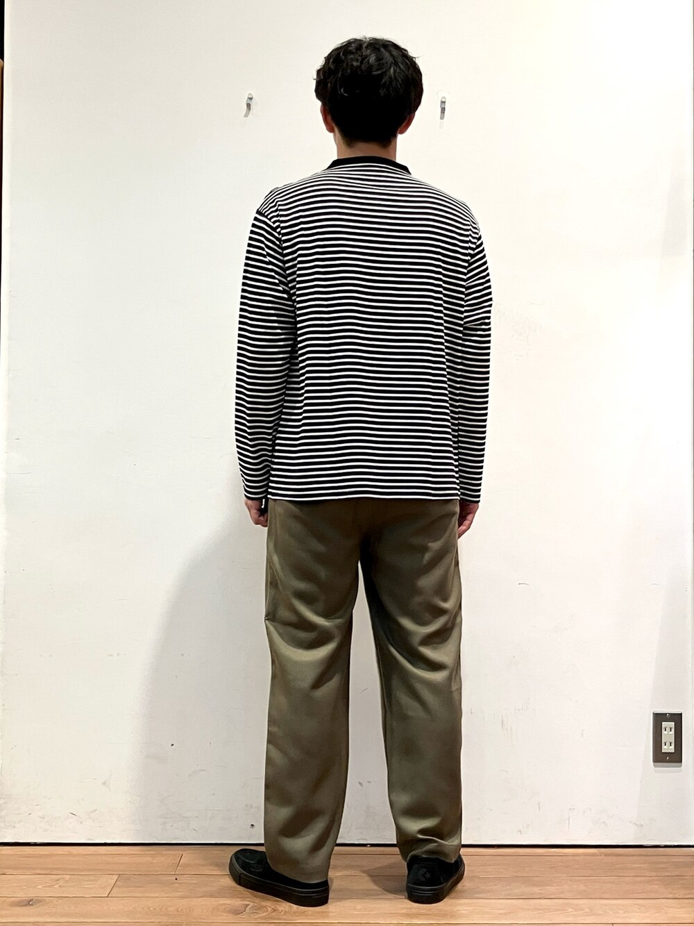 グレー系のカーディガン/ボレロ、ホワイト系のTシャツ/カットソー、グリーン系のパンツを着用したメンズの秋コーディネートの6枚目の写真