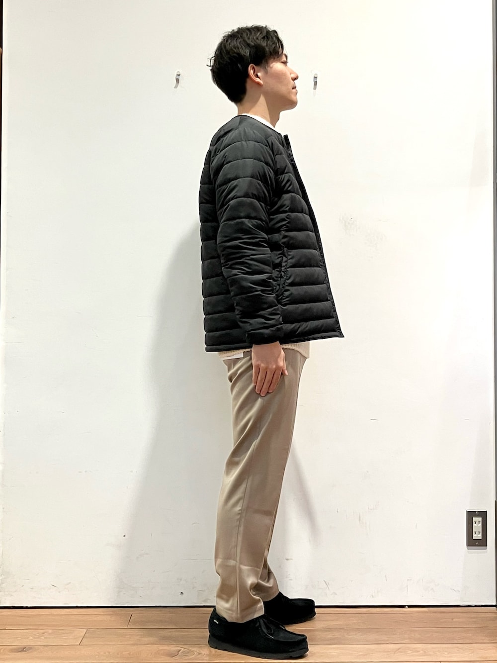 ブラック系のダウンジャケット/コート、ホワイト系のニット/セーター、ブラウン系のその他パンツを着用したメンズの冬コーディネートの2枚目の写真