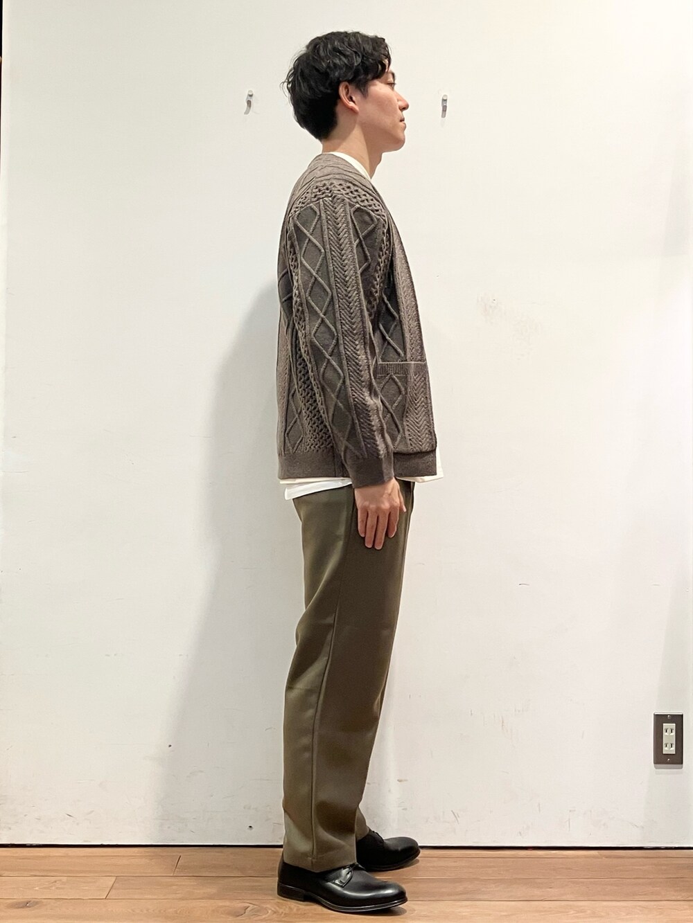 ブラウン系のカーディガン/ボレロ、ホワイト系のTシャツ/カットソー、ブラック系のドレスシューズを着用したメンズの秋コーディネートの2枚目の写真