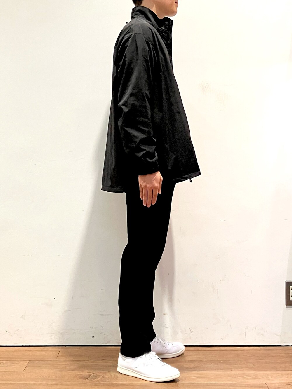 ブラック系のブルゾン、ブルー系のデニムパンツ、ホワイト系のスニーカーを着用したメンズの秋コーディネートの2枚目の写真