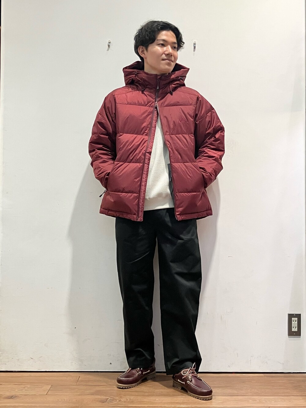 レッド系のダウンジャケット/コート、ベージュ系のTシャツ/カットソー、ブラック系のチノパンツを着用したメンズの秋コーディネートの2枚目の写真