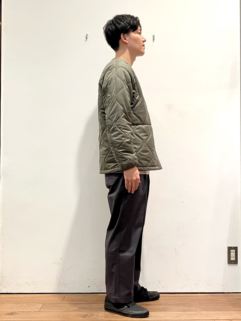 グリーン系のダウンジャケット/コート、ベージュ系のニット/セーター、グレー系のその他パンツを着用したメンズの秋コーディネートの2枚目の写真