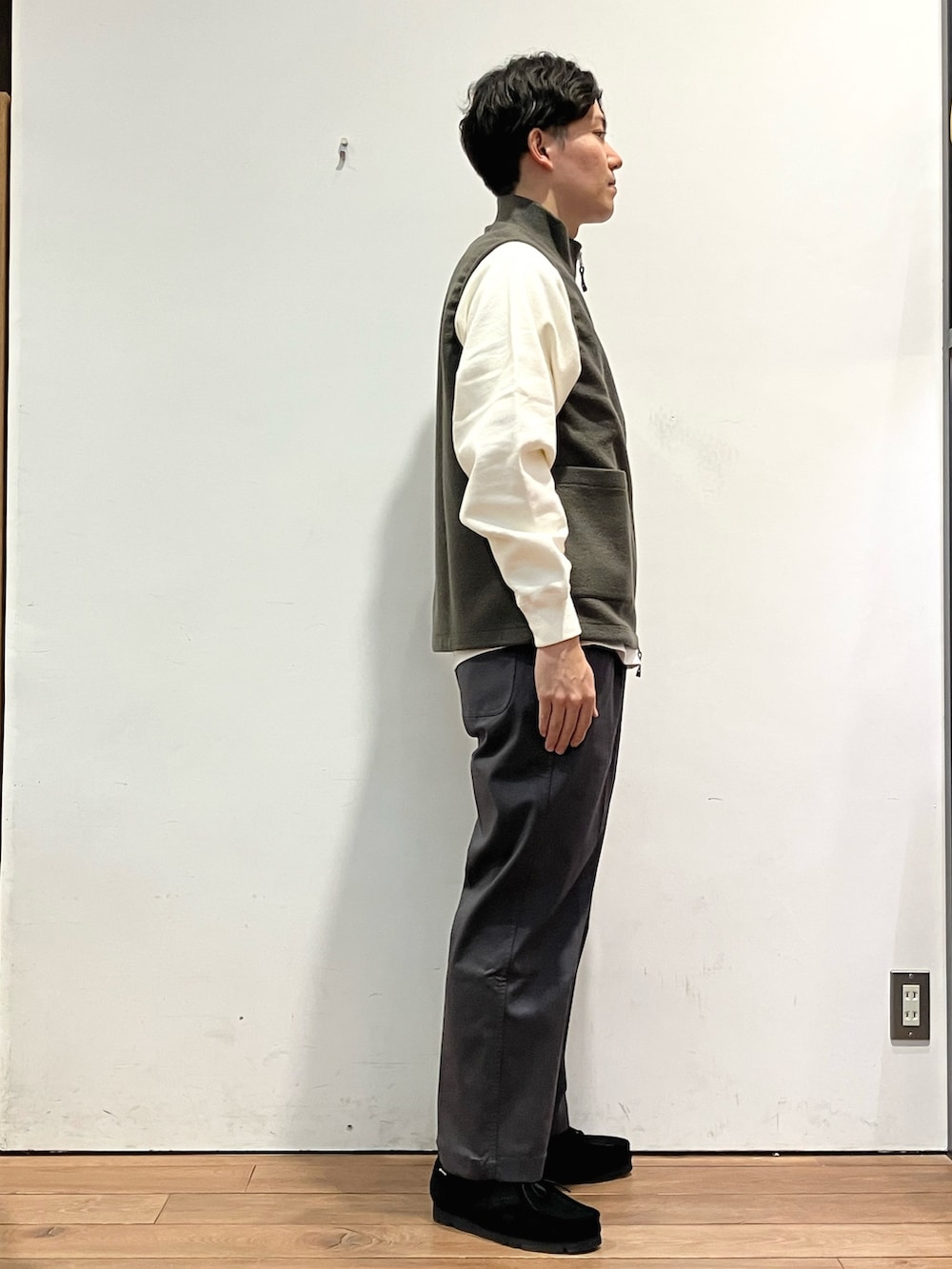 グリーン系のベスト、ホワイト系のスウェット、グレー系のその他パンツを着用したメンズの秋コーディネートの3枚目の写真