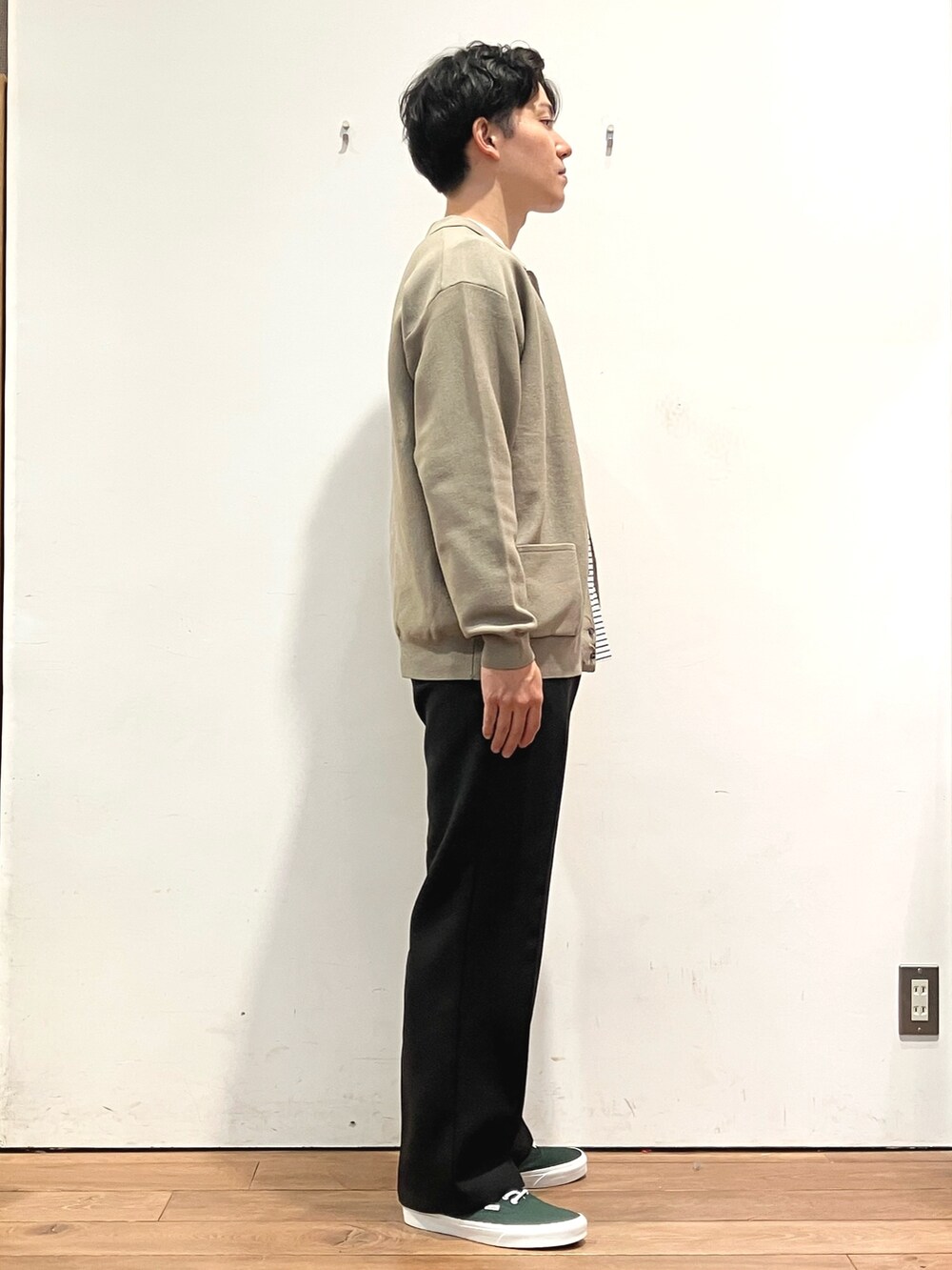 ブラウン系のカーディガン/ボレロ、ブラック系のTシャツ/カットソー、グリーン系のスニーカーを着用したメンズの秋コーディネートの2枚目の写真