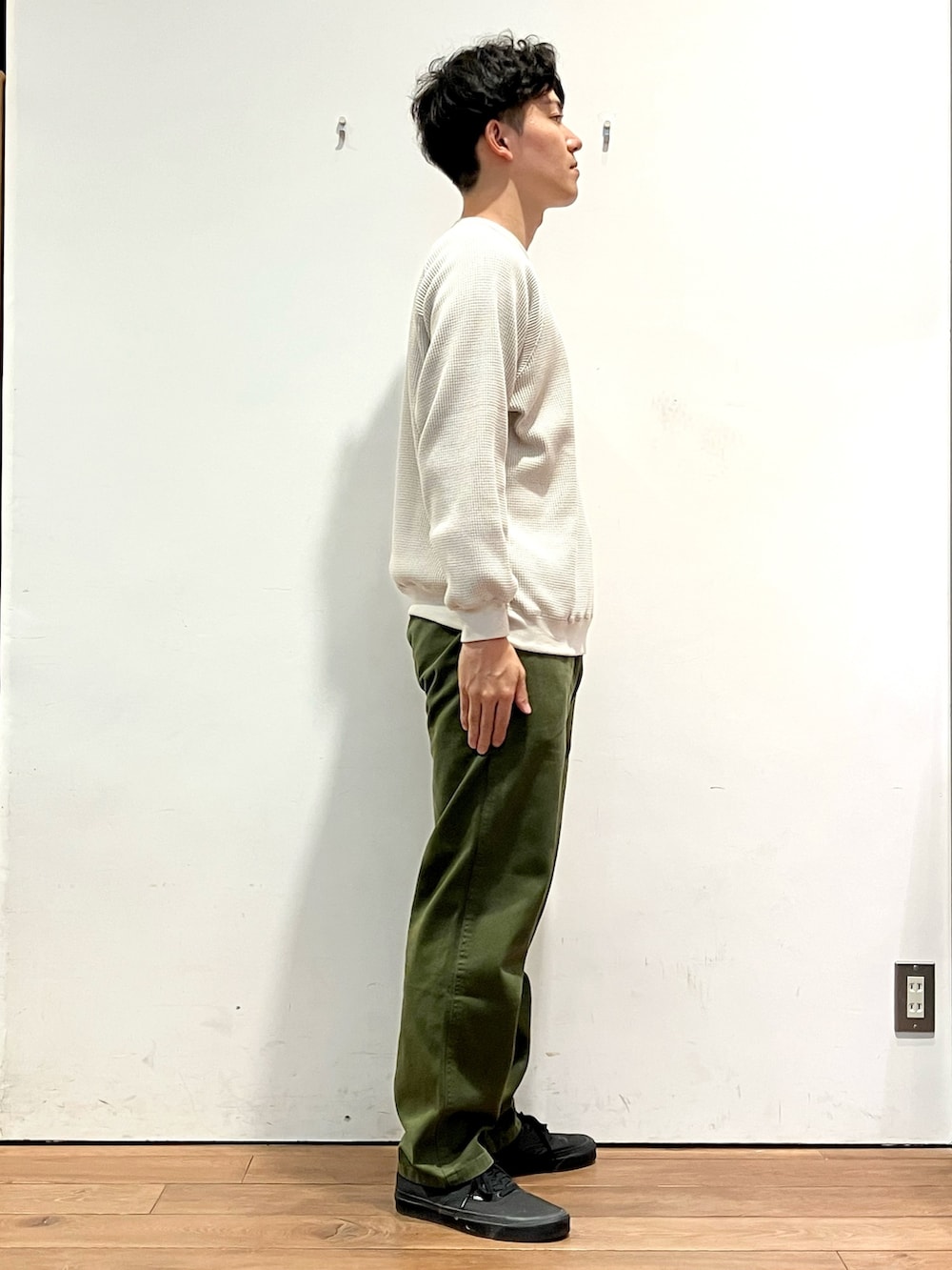 ベージュ系のTシャツ/カットソー、グリーン系のその他パンツ、ブラック系のスニーカーを着用したメンズの秋コーディネートの2枚目の写真