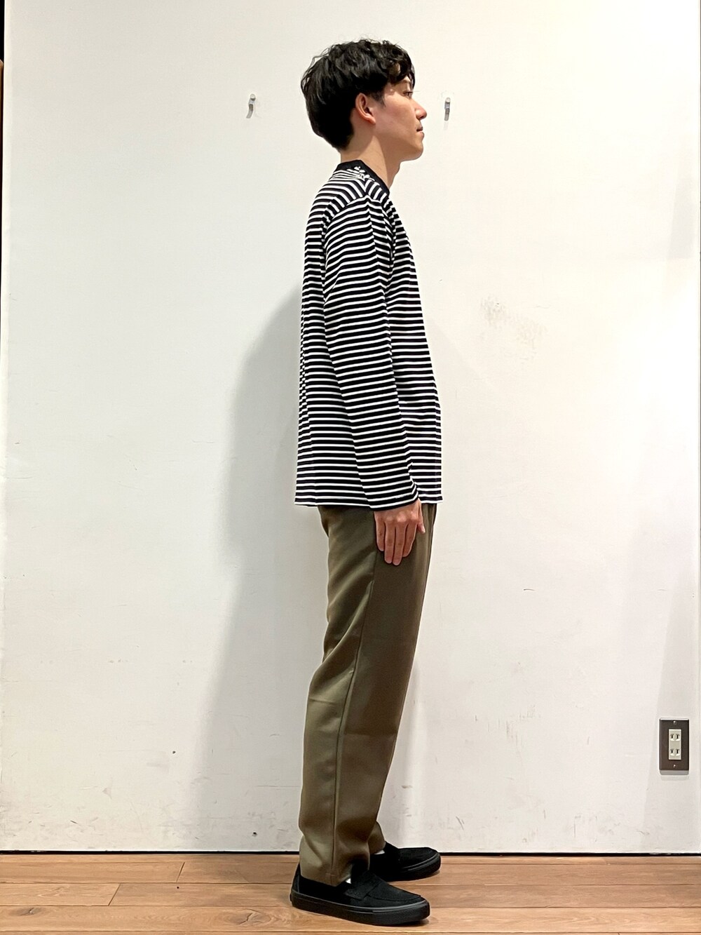 グレー系のカーディガン/ボレロ、ホワイト系のTシャツ/カットソー、グリーン系のパンツを着用したメンズの秋コーディネートの5枚目の写真