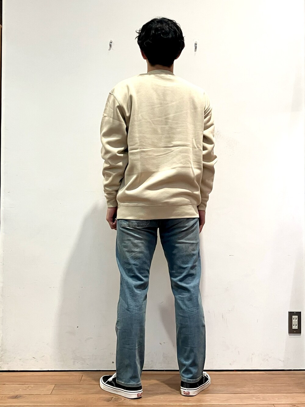 ブラック系のダウンジャケット/コート、ベージュ系のスウェット、ブルー系のその他パンツを着用したメンズの秋コーディネートの6枚目の写真