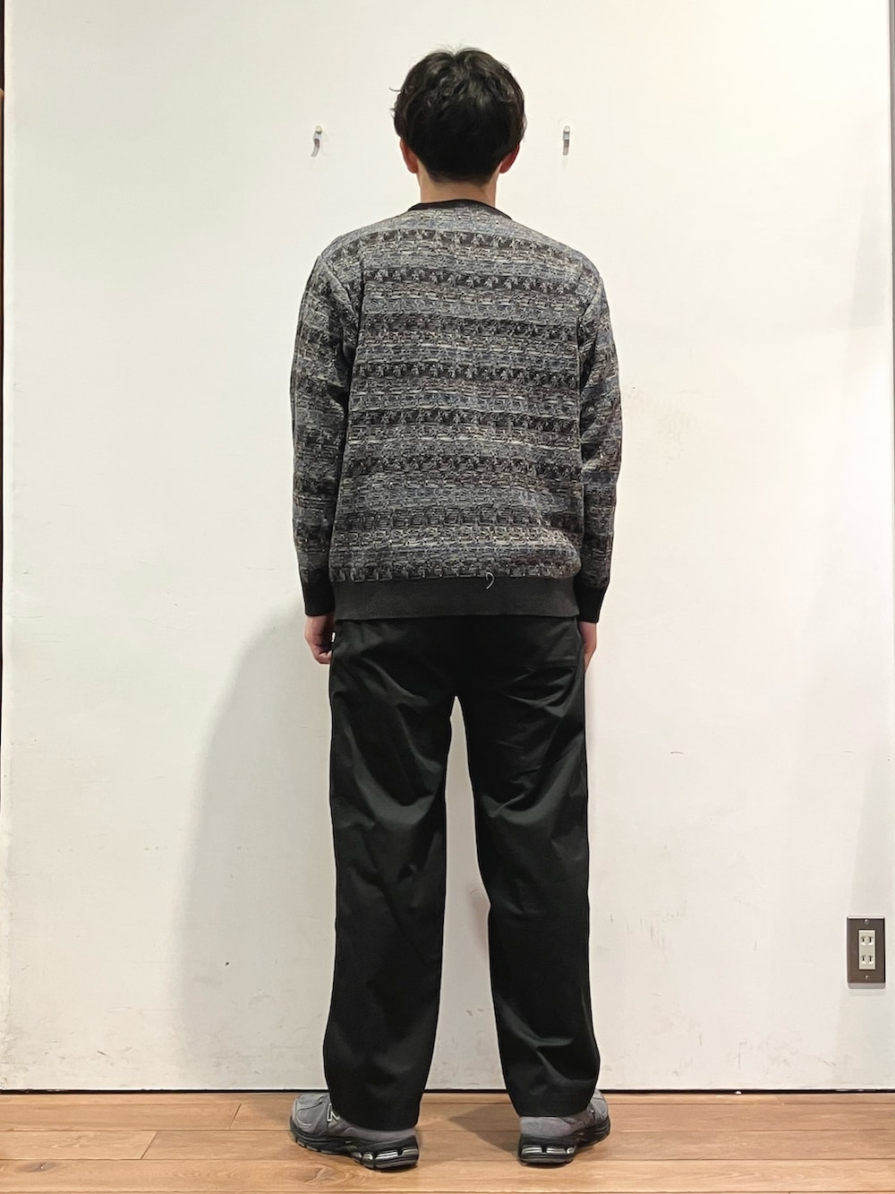 ブルー系のダウンジャケット/コート、ブラック系のチノパンツ、グレー系のニット/セーターを着用したメンズの秋コーディネートの6枚目の写真