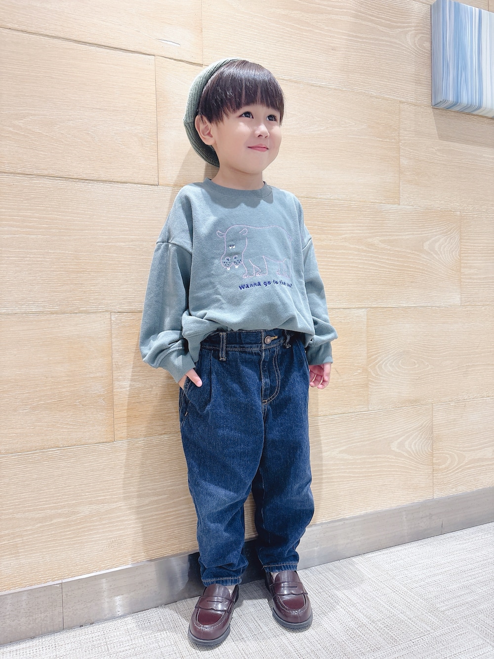 ブラック系のショルダーバッグ、グリーン系のスウェット、ブルー系のデニムパンツを着用したキッズの秋コーディネートの2枚目の写真