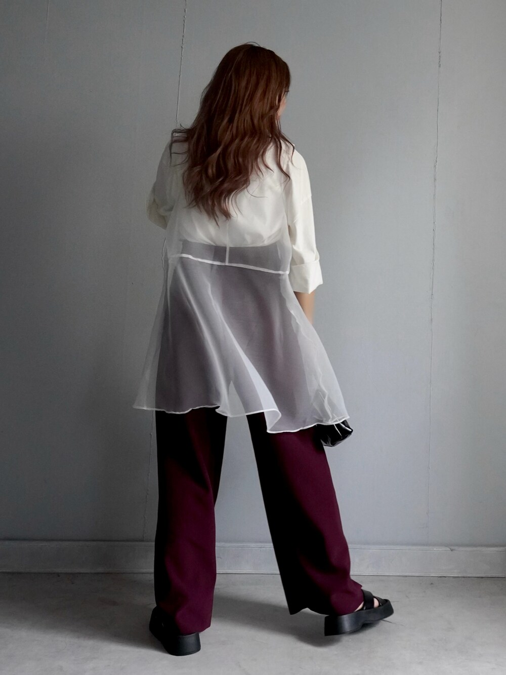 ブラック系のバッグ、レッド系のパンツ、ホワイト系のチュニックを着用したレディースの春コーディネートの3枚目の写真