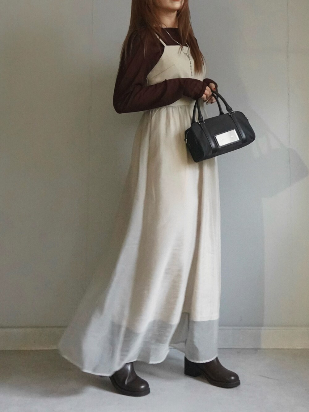 ベージュ系のワンピース、ブルー系のデニムパンツ、ブラウン系のトップスを着用したレディースの春コーディネートの5枚目の写真