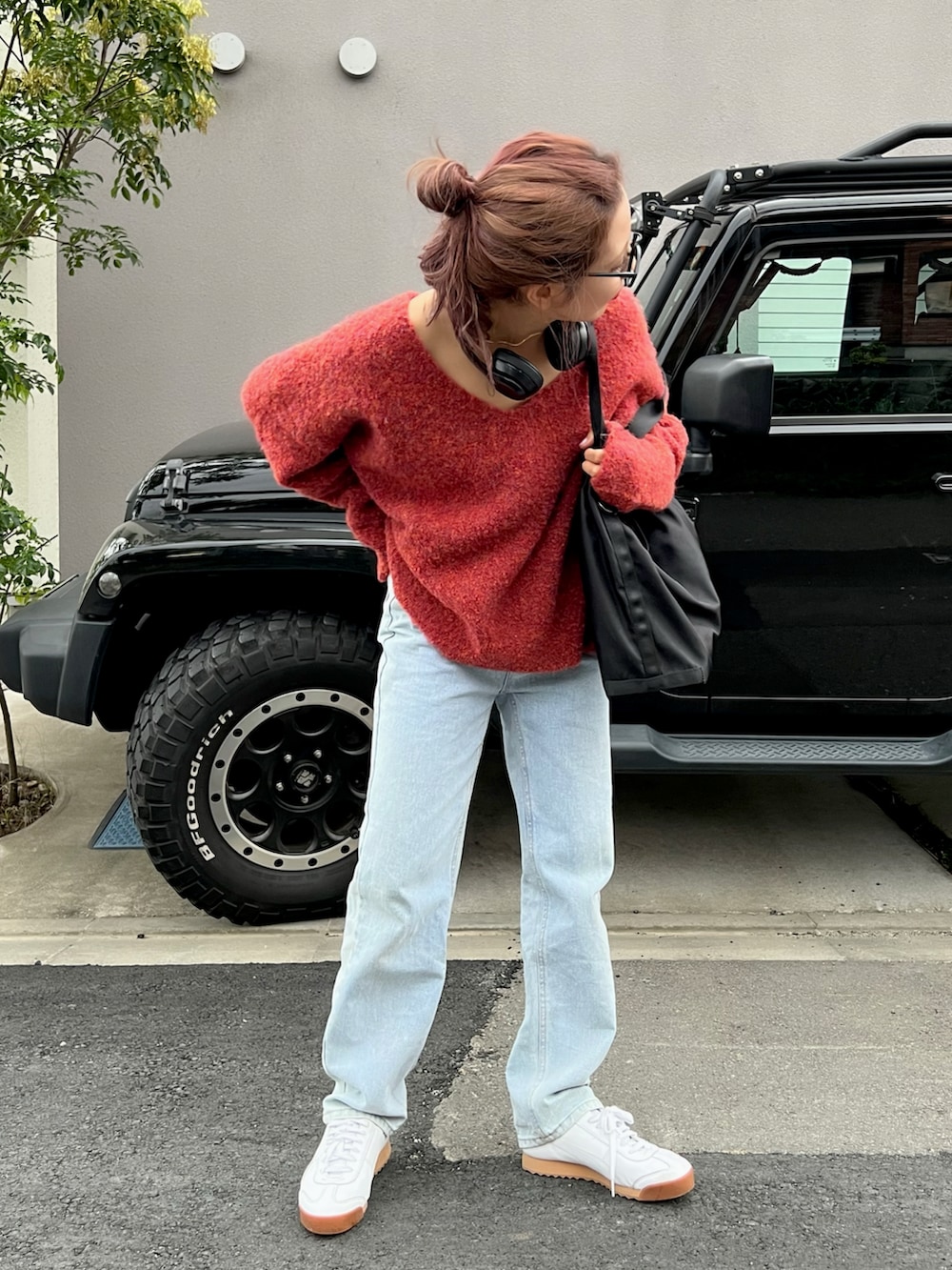 ホワイト系のスニーカー、レッド系のニット/セーター、ブルー系のデニムパンツを着用したレディースの夏コーディネートの3枚目の写真