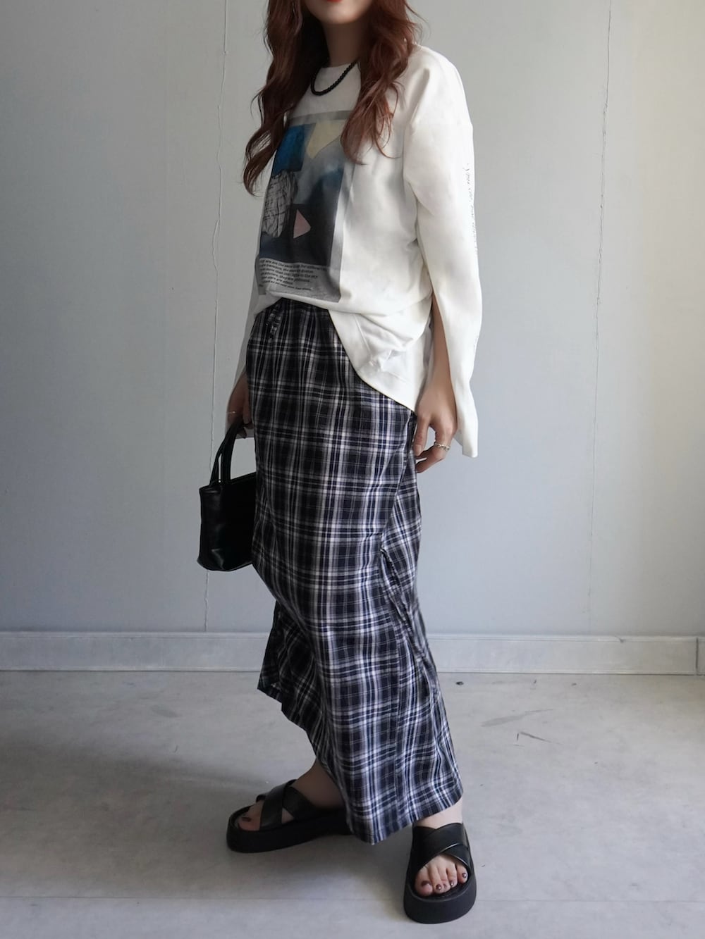 ブラック系のサンダル、ブラック系のスカート、ホワイト系のTシャツ/カットソーを着用したレディースの春コーディネートの3枚目の写真