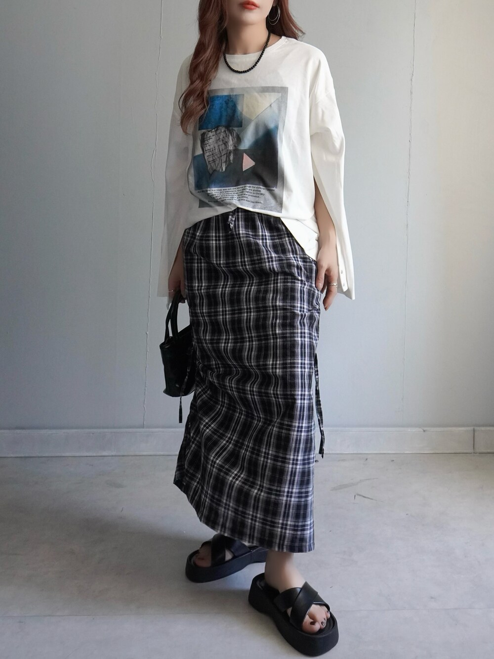 ブラック系のサンダル、ブラック系のスカート、ホワイト系のTシャツ/カットソーを着用したレディースの春コーディネートの2枚目の写真