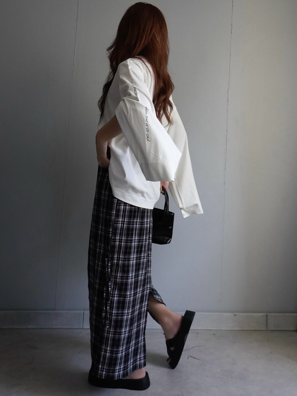 ブラック系のサンダル、ブラック系のスカート、ホワイト系のTシャツ/カットソーを着用したレディースの春コーディネートの5枚目の写真