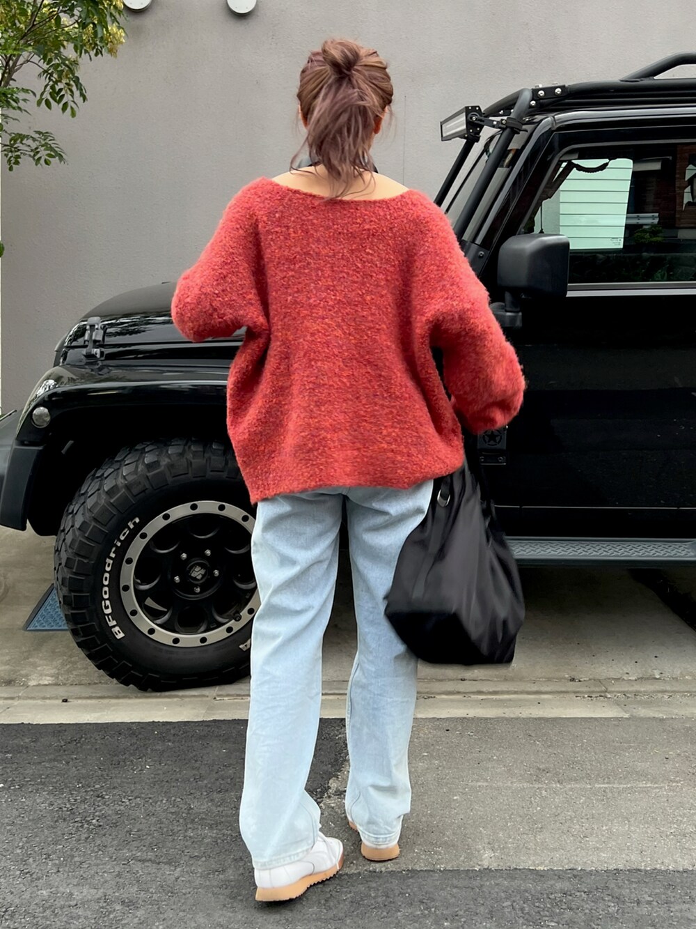 ホワイト系のスニーカー、レッド系のニット/セーター、ブルー系のデニムパンツを着用したレディースの夏コーディネートの4枚目の写真