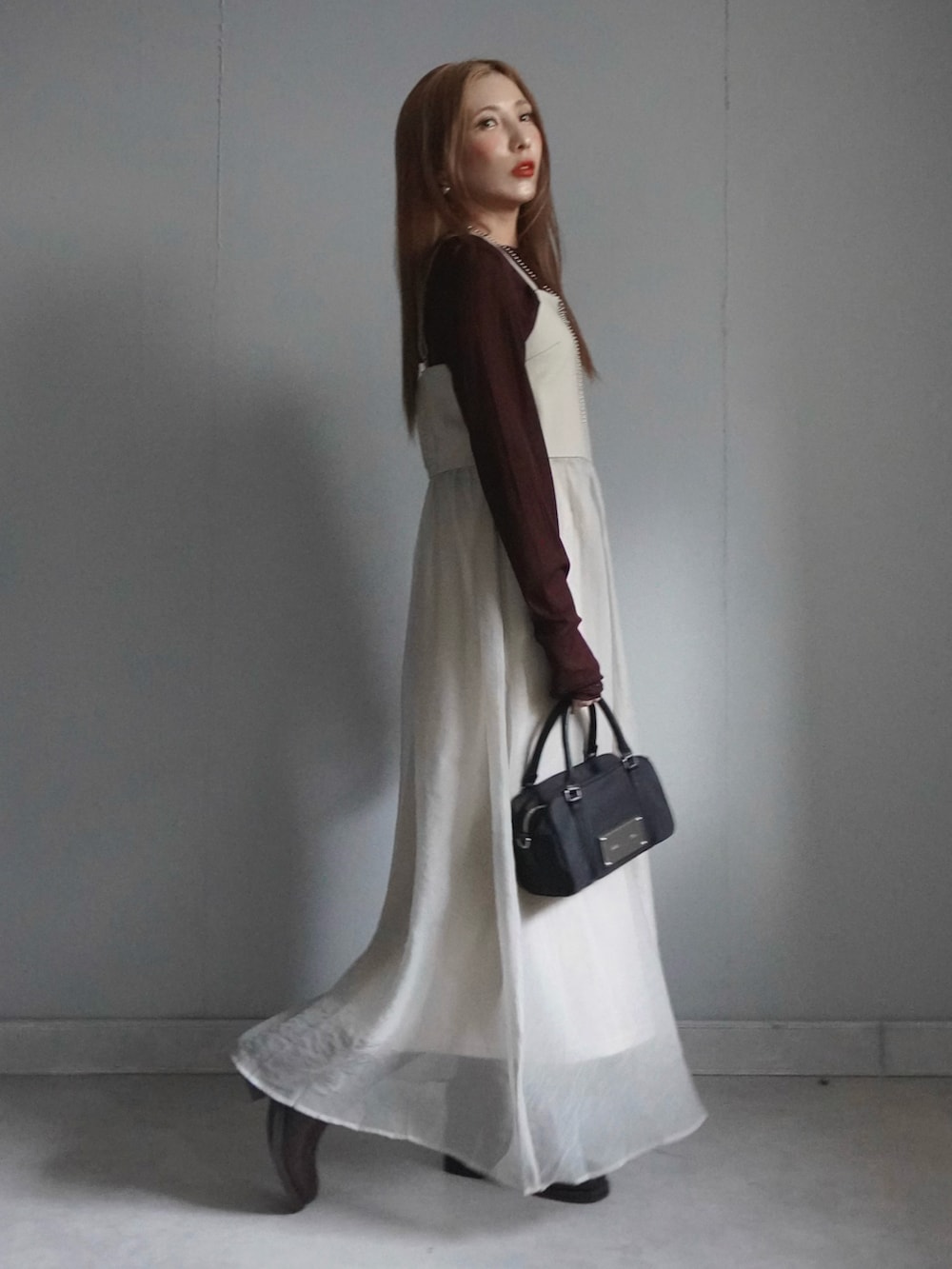 ベージュ系のワンピース、ブルー系のデニムパンツ、ブラウン系のトップスを着用したレディースの春コーディネートの3枚目の写真