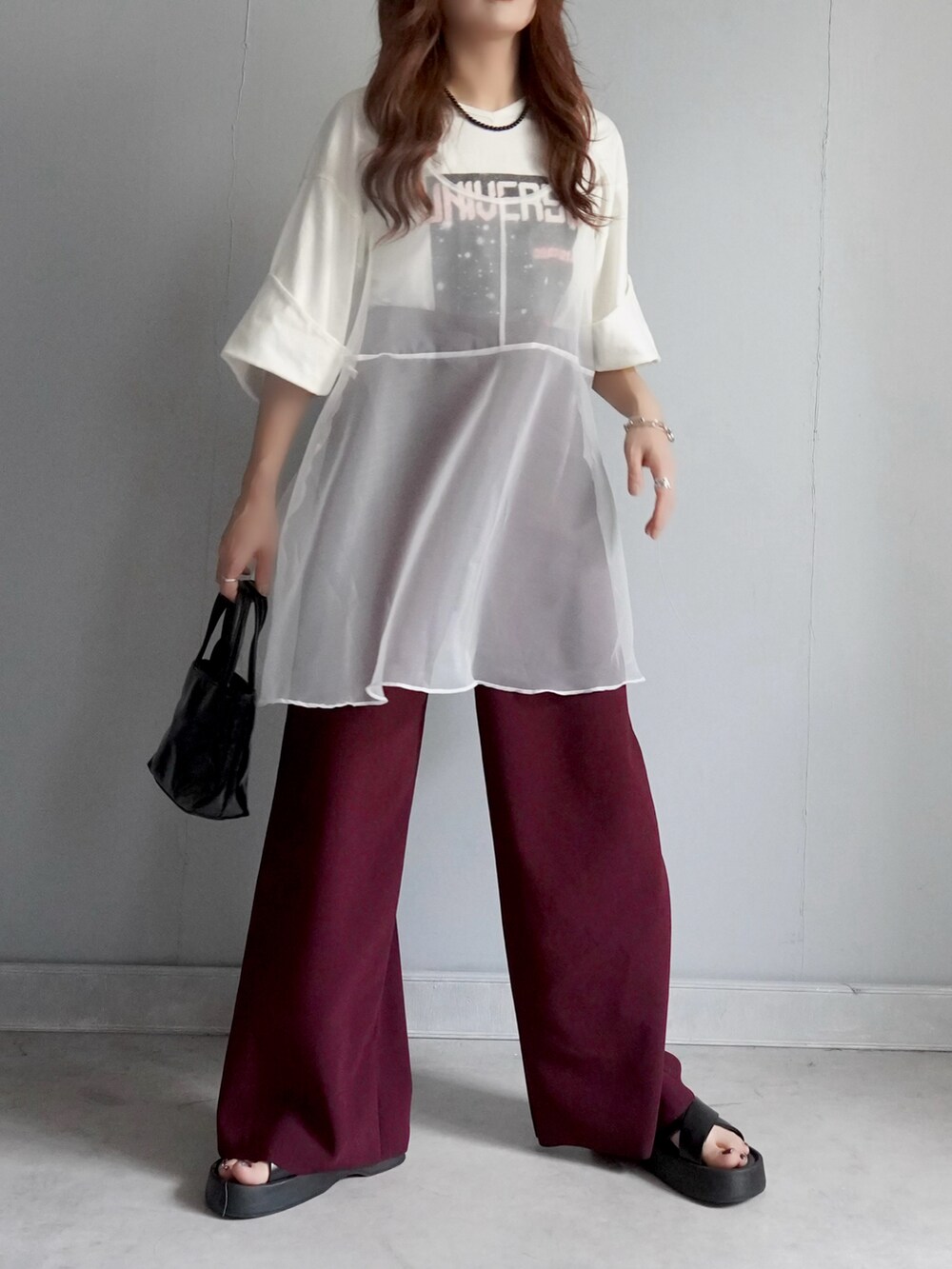 ブラック系のバッグ、レッド系のパンツ、ホワイト系のチュニックを着用したレディースの春コーディネートの4枚目の写真