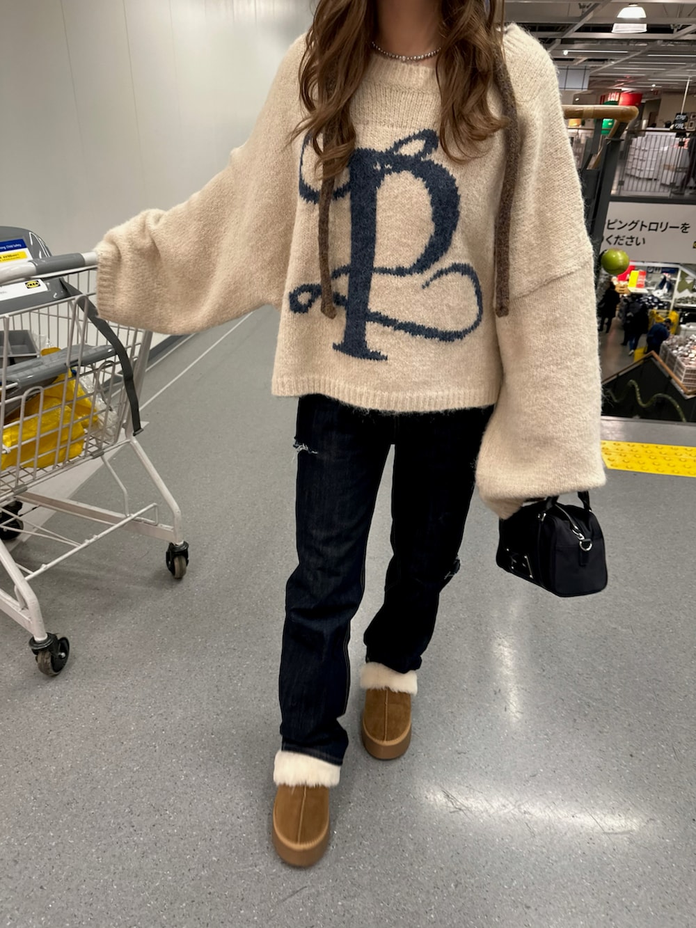 ブルー系のデニムパンツ、ベージュ系のニット/セーター、ブルー系のデニムパンツを着用したレディースの冬コーディネートの2枚目の写真