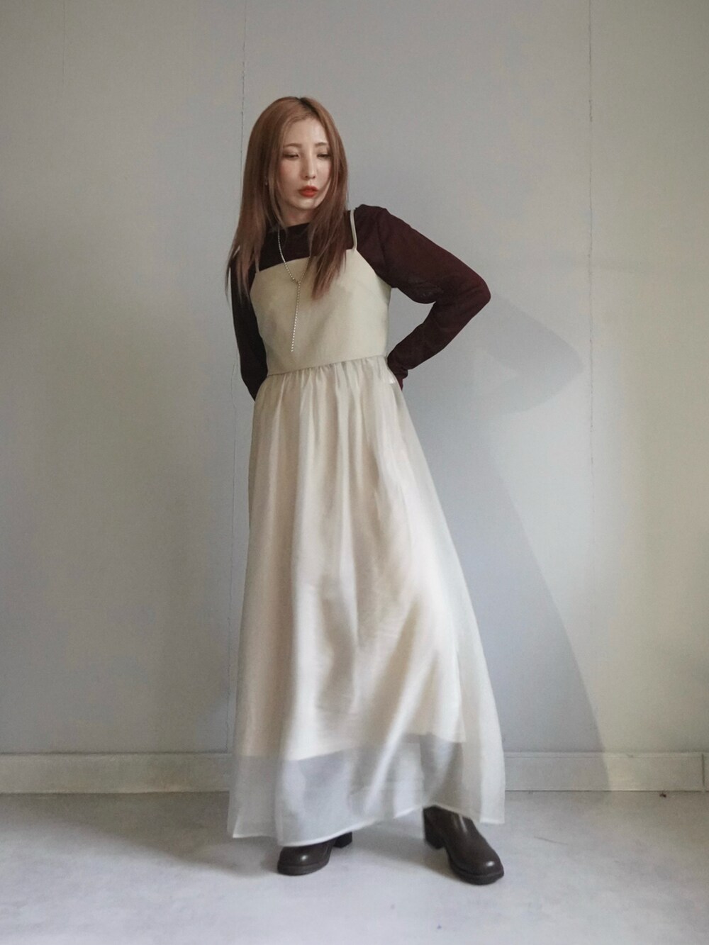 ベージュ系のワンピース、ブルー系のデニムパンツ、ブラウン系のトップスを着用したレディースの春コーディネートの4枚目の写真