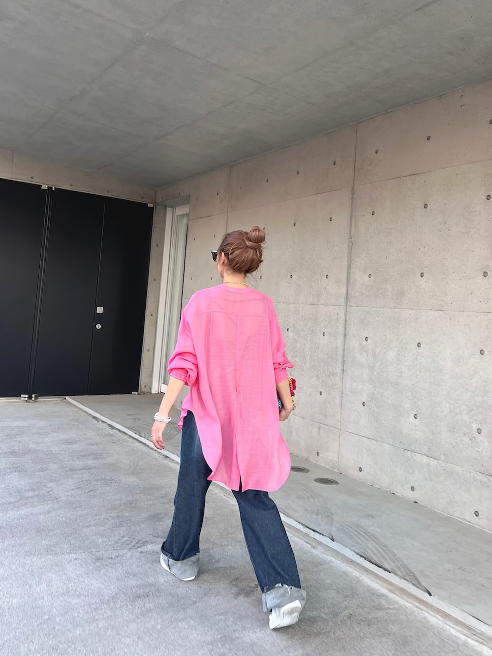 ブルー系のデニムパンツ、ホワイト系のスニーカー、ピンク系のシャツ/ブラウスを着用したレディースの春コーディネートの3枚目の写真