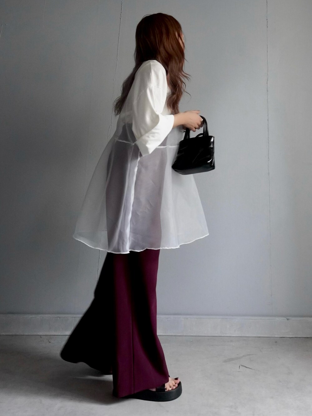 ブラック系のバッグ、レッド系のパンツ、ホワイト系のチュニックを着用したレディースの春コーディネートの2枚目の写真