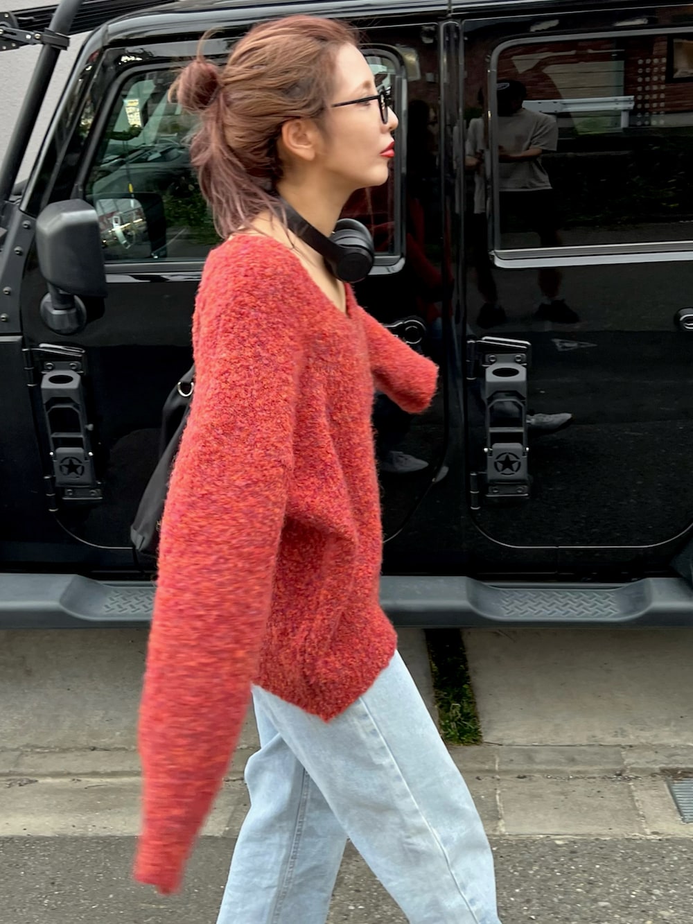 ホワイト系のスニーカー、レッド系のニット/セーター、ブルー系のデニムパンツを着用したレディースの夏コーディネートの2枚目の写真