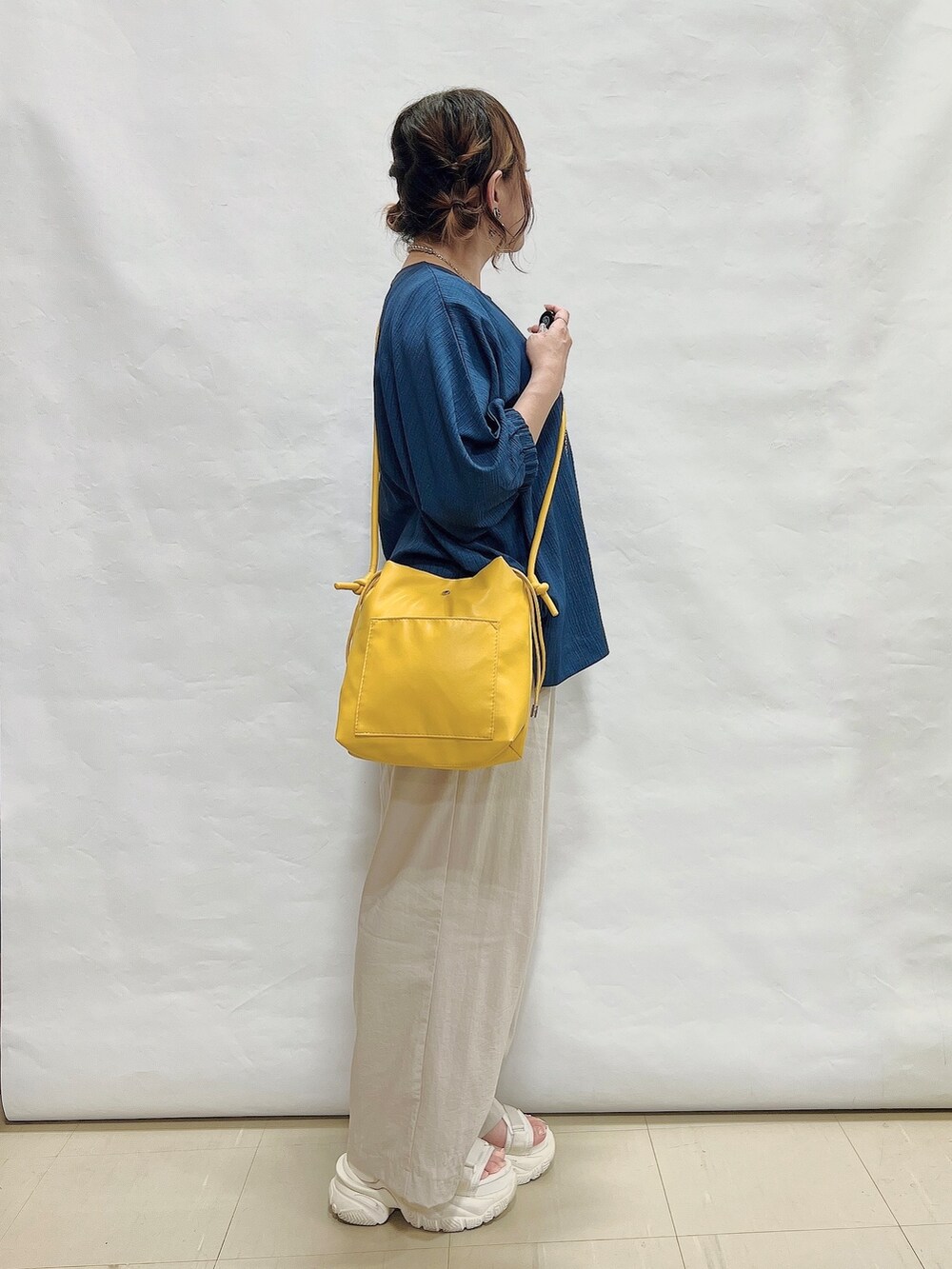 ブルー系のシャツ/ブラウス、ベージュ系のその他パンツ、イエロー系のショルダーバッグを着用したレディースの夏コーディネートの2枚目の写真