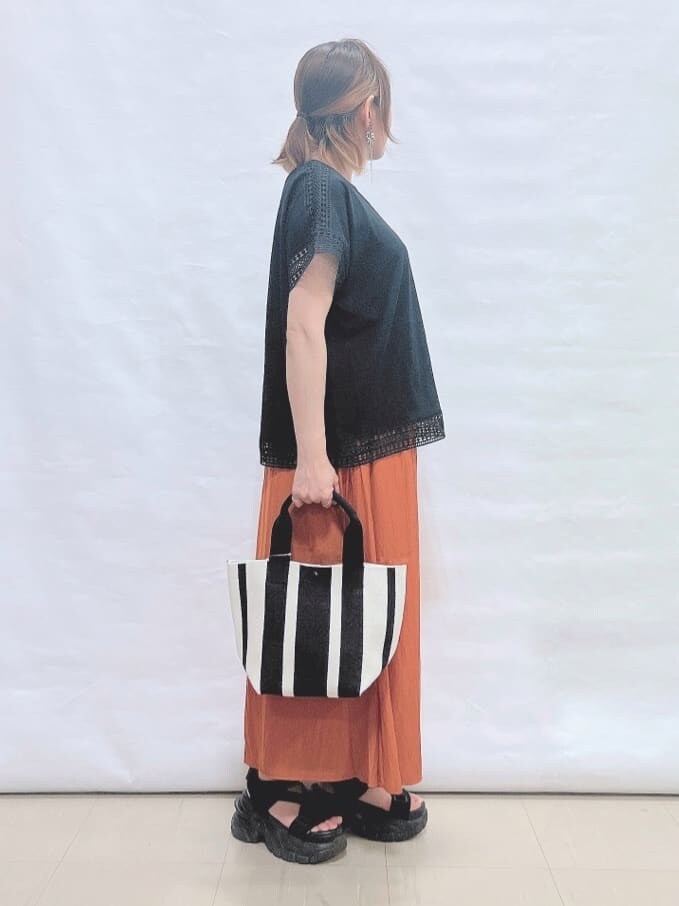 ブラック系のTシャツ/カットソー、オレンジ系のその他パンツ、ブラック系のトートバッグを着用したレディースの夏コーディネートの2枚目の写真