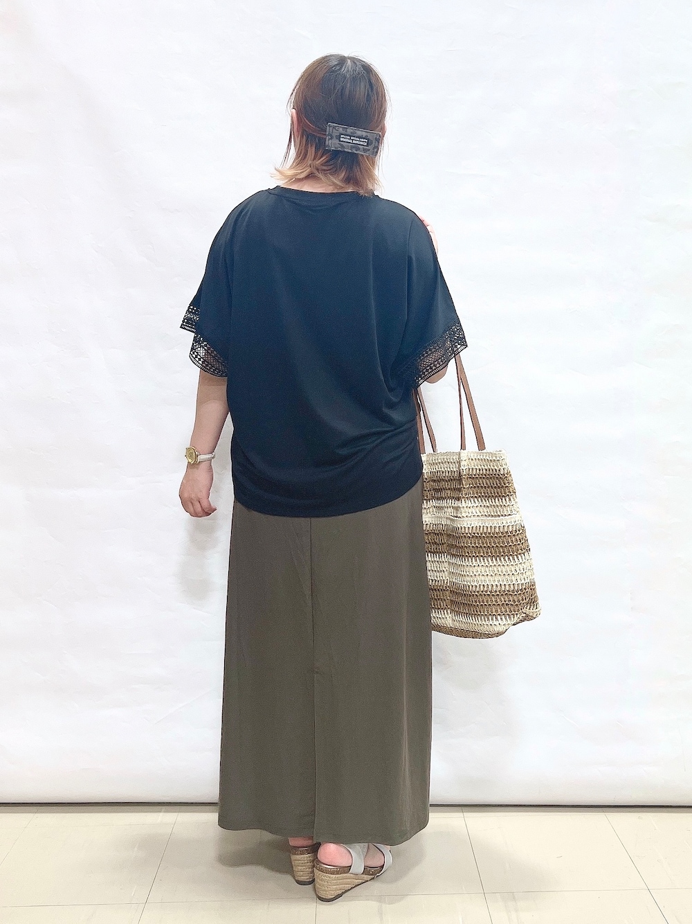 ブラック系のTシャツ/カットソー、グリーン系のスカート、シルバー系のサンダルを着用したレディースの夏コーディネートの3枚目の写真