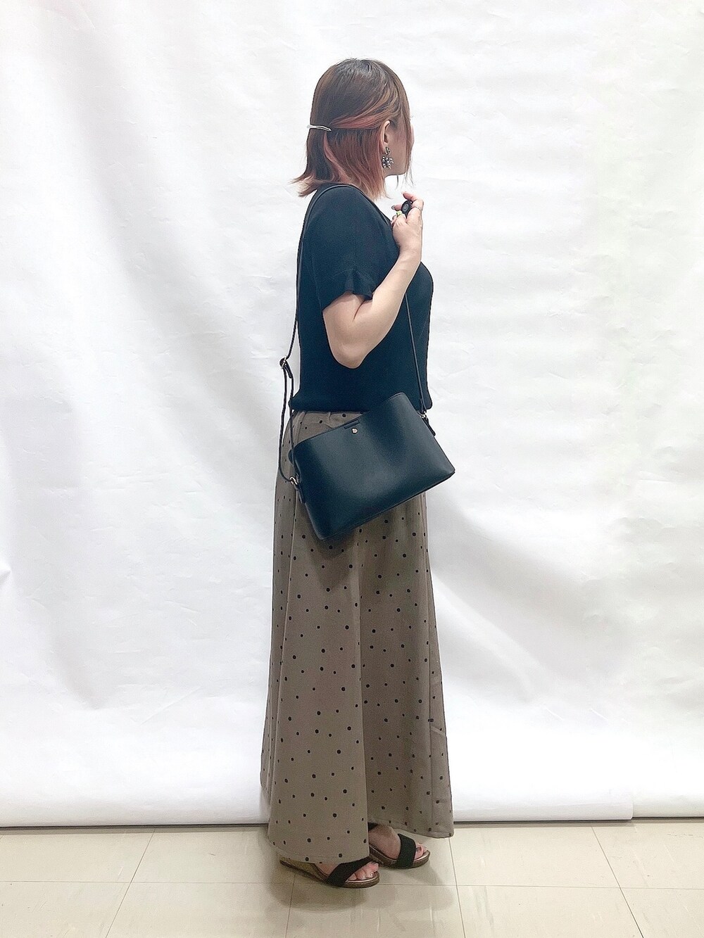 ブラック系のニット/セーター、ブラウン系のスカート、ブラック系のサンダルを着用したレディースの夏コーディネートの2枚目の写真