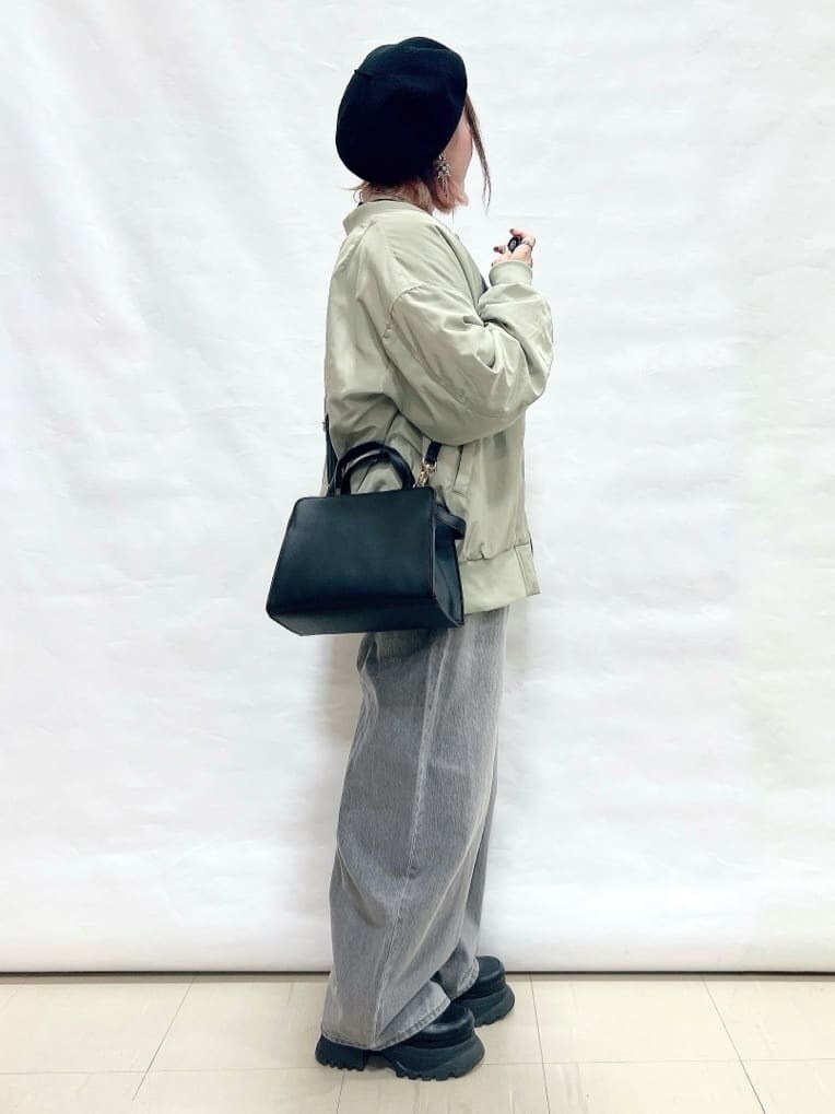 グリーン系のブルゾン、ブラック系のニット/セーター、グレー系のデニムパンツを着用したレディースの冬コーディネートの2枚目の写真