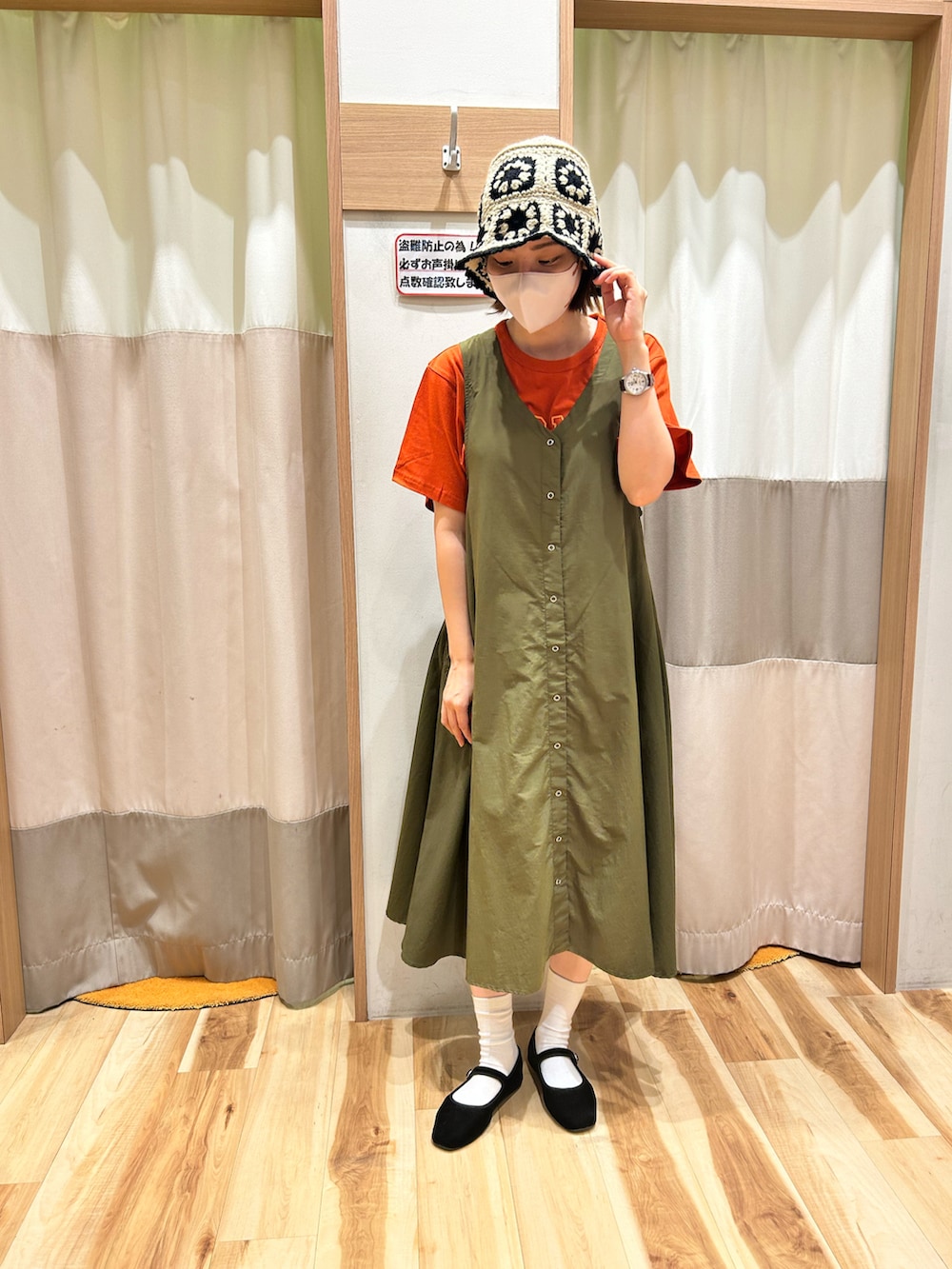 グリーン系のワンピース、オレンジ系のTシャツ/カットソー、ベージュ系の帽子を着用したレディースの夏コーディネートの2枚目の写真