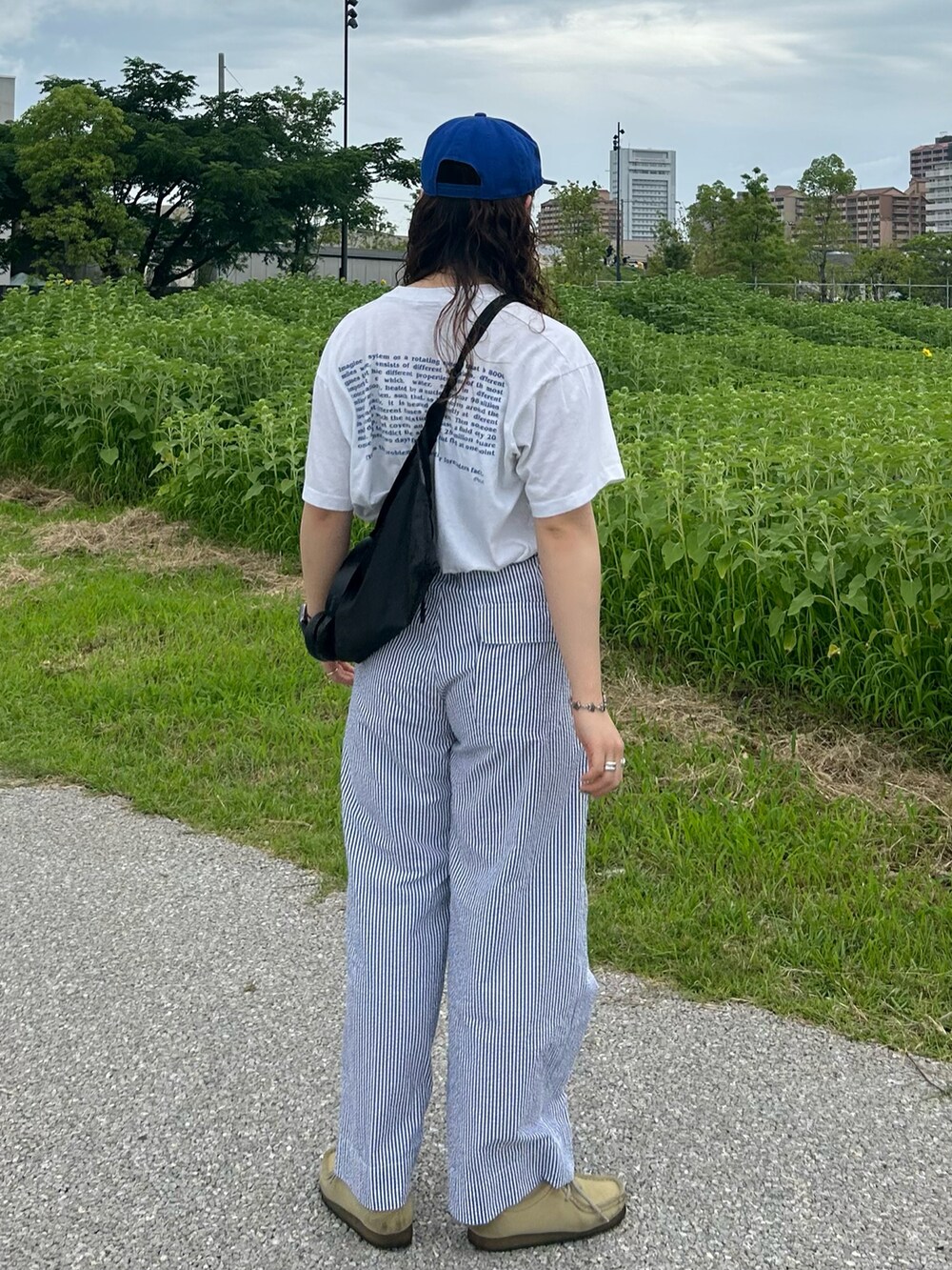 ブルー系のスラックス、ベージュ系のモカシン/デッキシューズ、ホワイト系のTシャツ/カットソーを着用したレディースの夏コーディネートの2枚目の写真