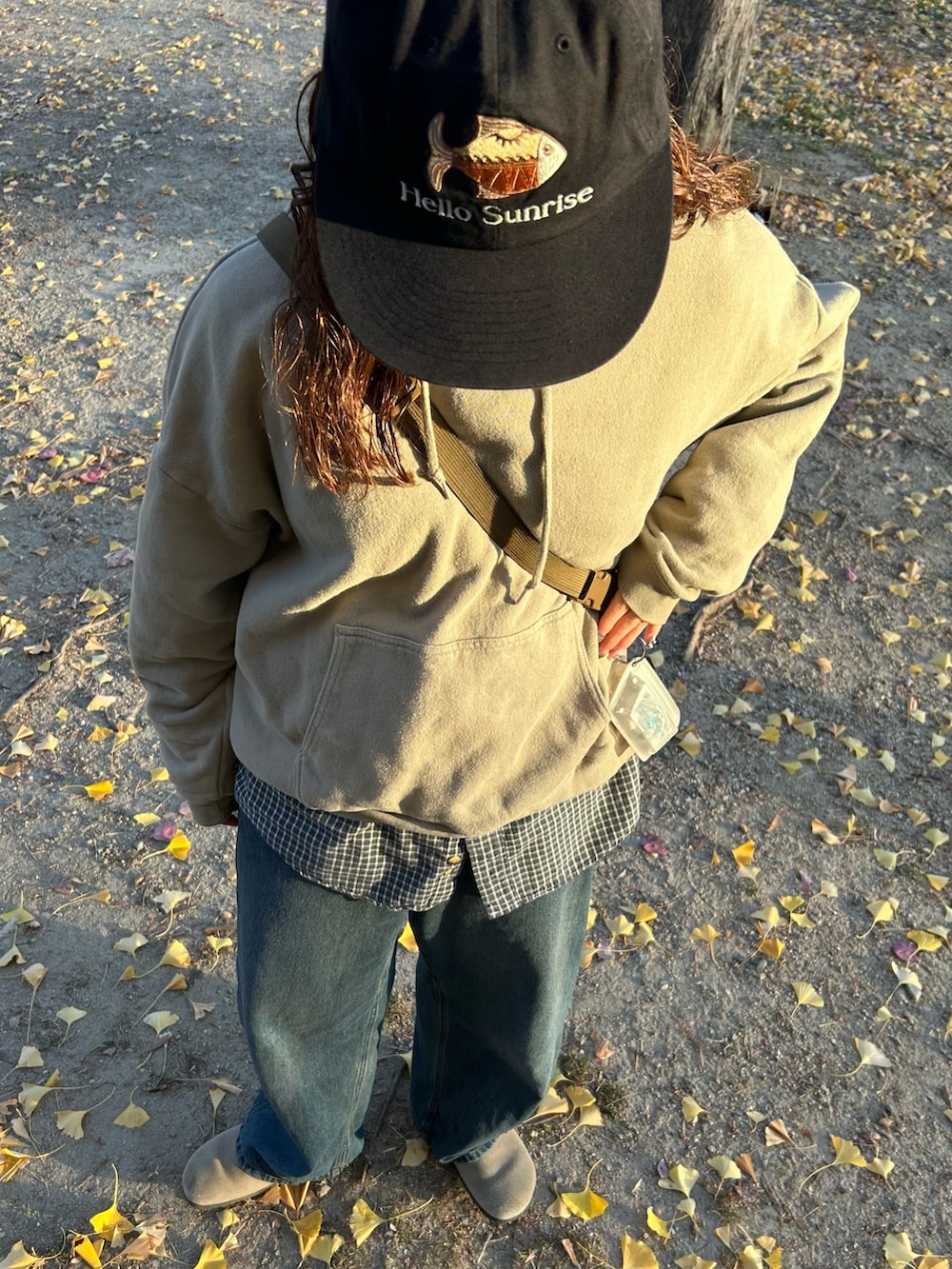 ブルー系のデニムパンツ、ベージュ系のパーカー、ブラック系のショルダーバッグを着用したレディースの冬コーディネートの4枚目の写真