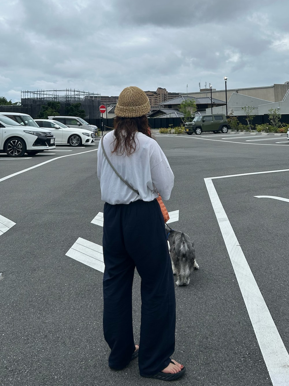 ホワイト系のTシャツ/カットソー、オレンジ系のかごバッグ、ブラック系のサンダルを着用したレディースの夏コーディネートの2枚目の写真