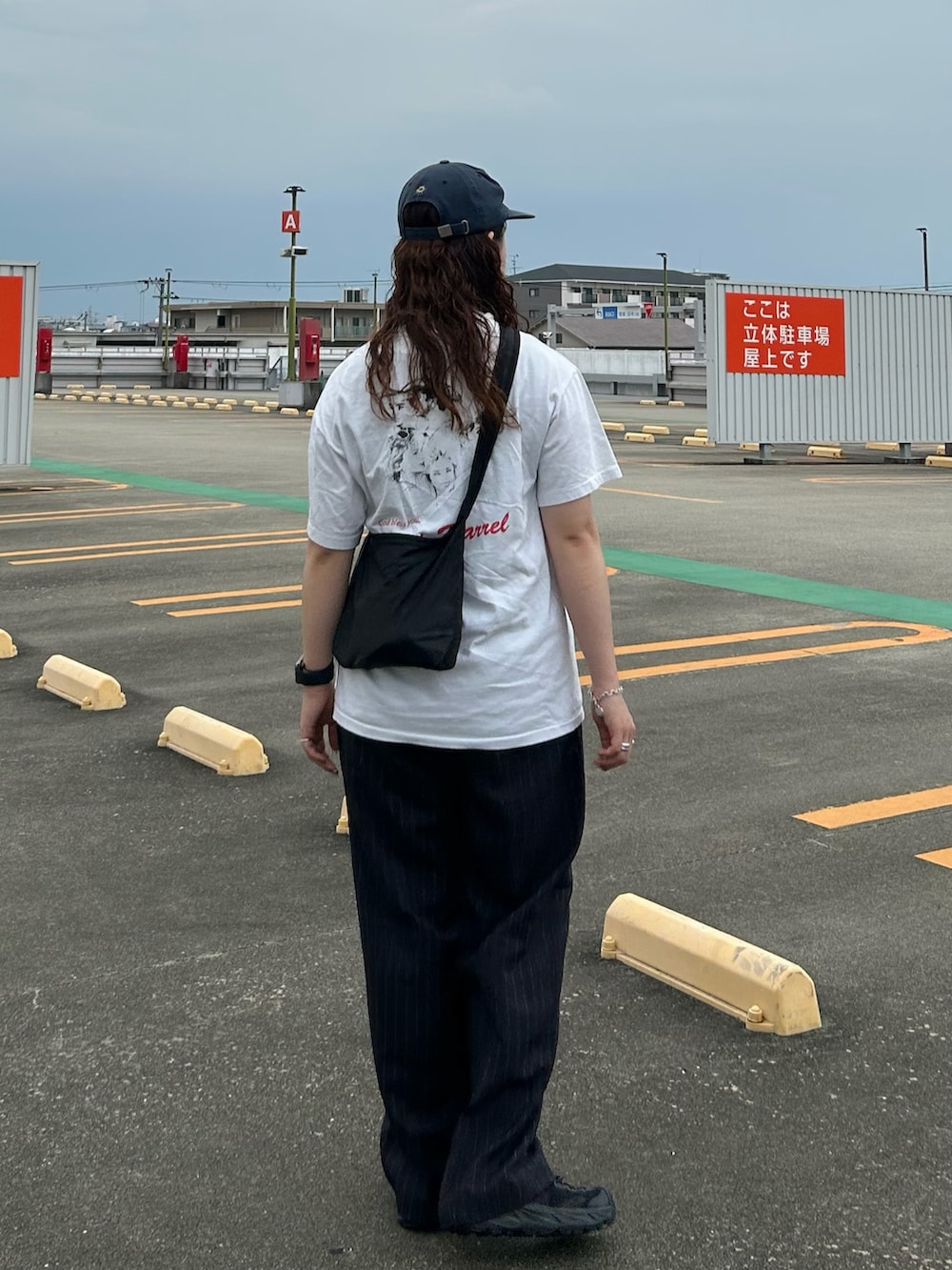 ブラック系のショルダーバッグ、ホワイト系のTシャツ/カットソー、ブルー系のスラックスを着用したレディースの夏コーディネートの2枚目の写真