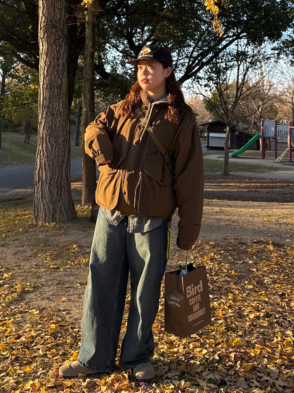 ブルー系のデニムパンツ、ベージュ系のパーカー、ブラック系のショルダーバッグを着用したレディースの冬コーディネートの2枚目の写真