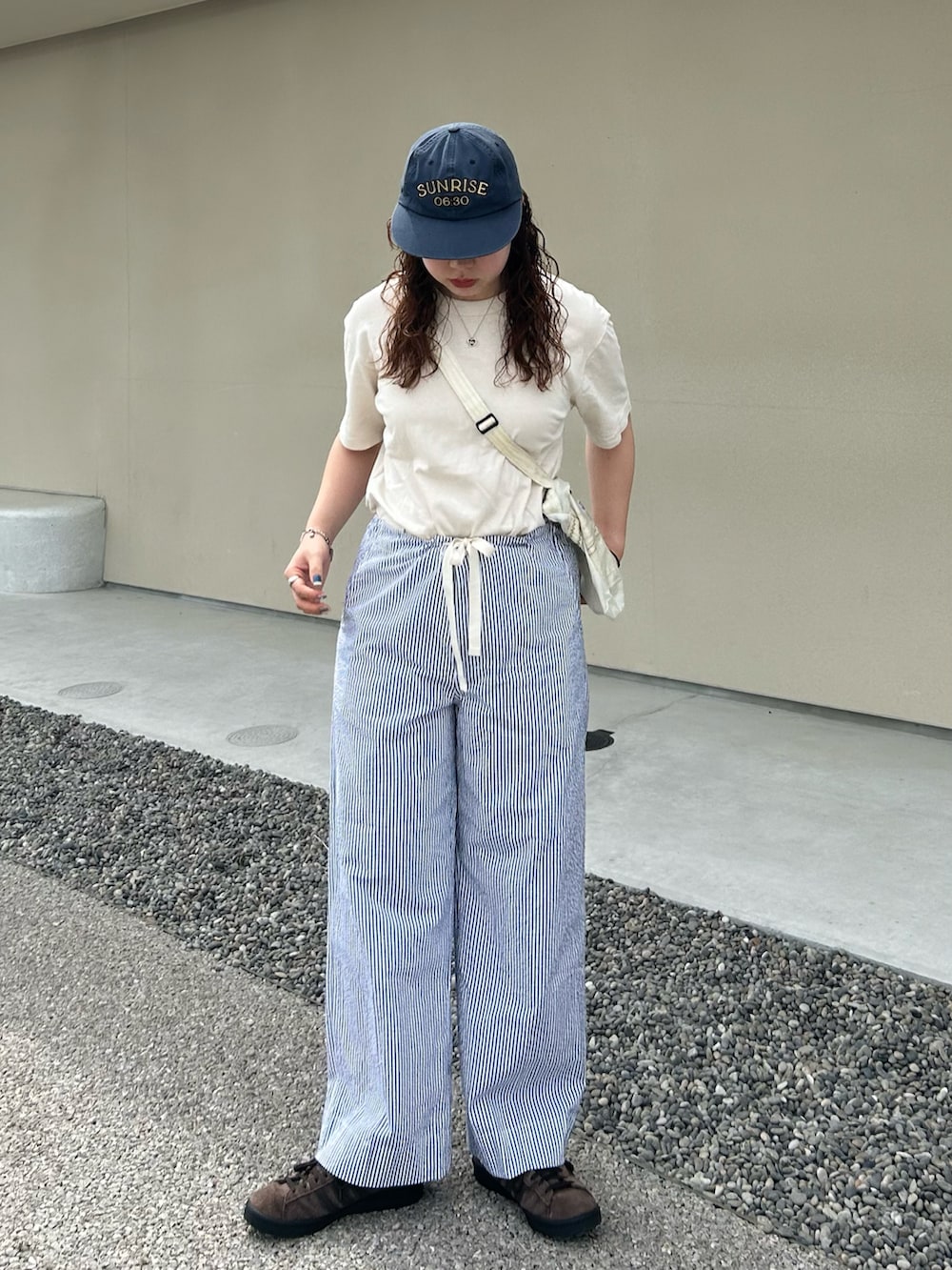 ホワイト系のTシャツ/カットソー、ブルー系のスラックス、ブラウン系のスニーカーを着用したレディースの夏コーディネートの3枚目の写真